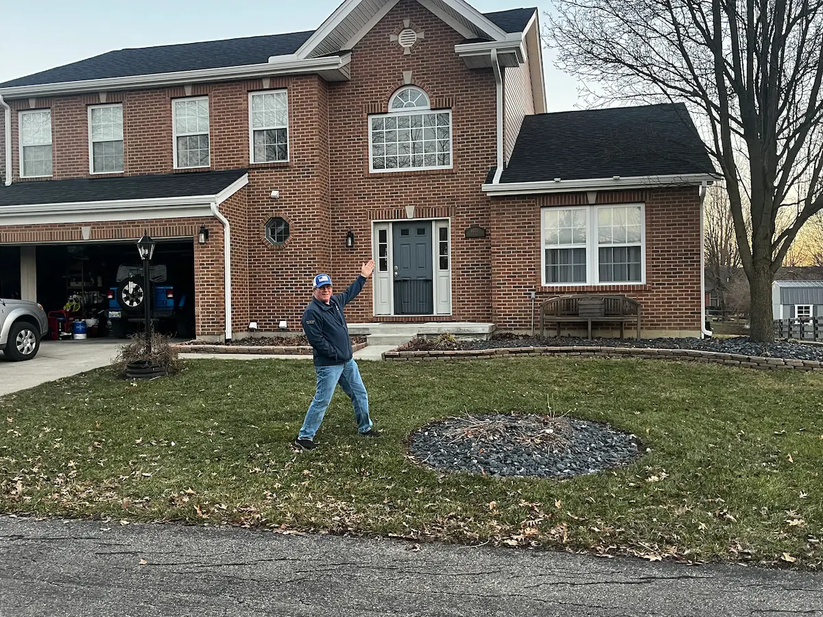 A very happy J Bucks Gutters customer standing in front of their home